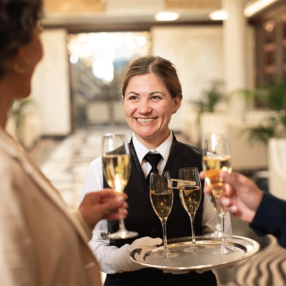 Regent Seven Seas Cruises crew member giving out champagne glasses