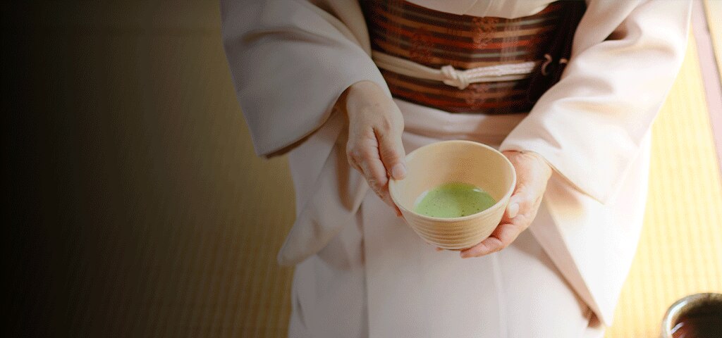 Geisha holding a cup of green matcha tea