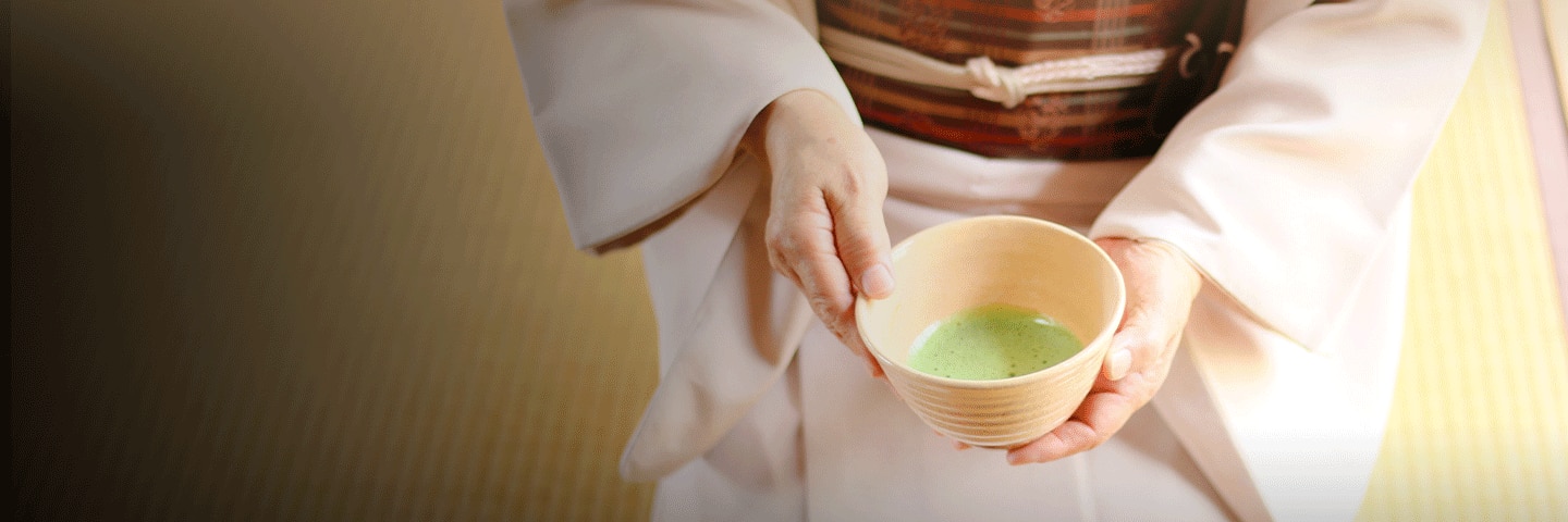 Geisha holding a cup of green matcha tea