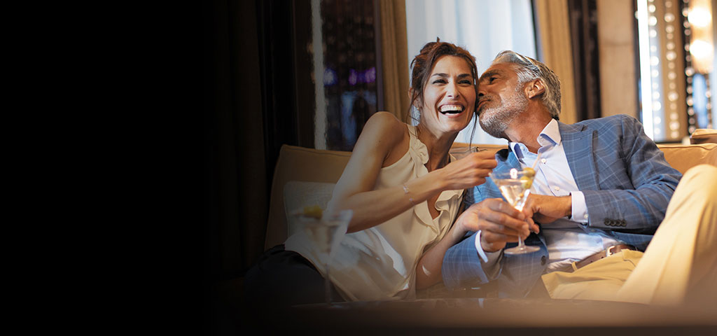 man kissing laughing woman on the cheek holding a martini glass on a new years eve holiday cruise