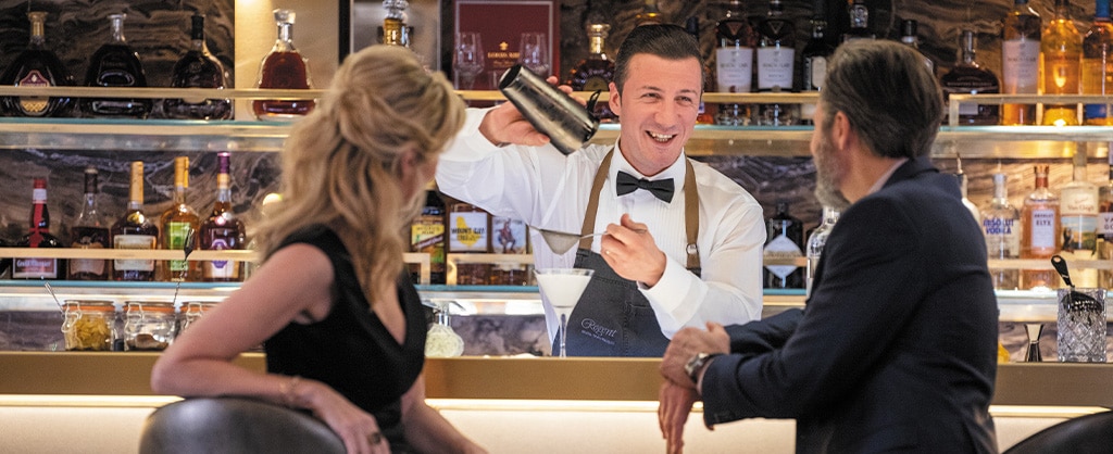 a couple talking at the bar while bar tender pours them a drink