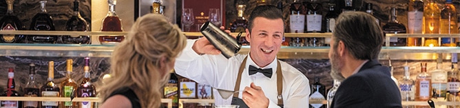 a couple talking at the bar while bar tender pours them a drink