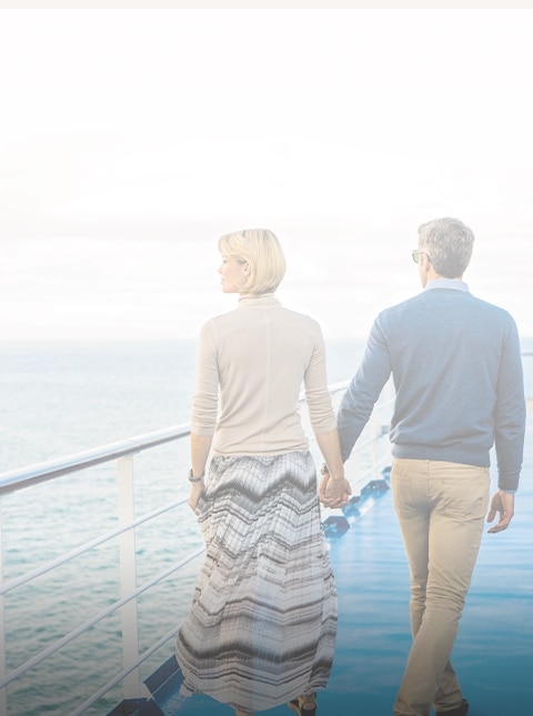 Couple holding hands walking on a Regent cruise ship