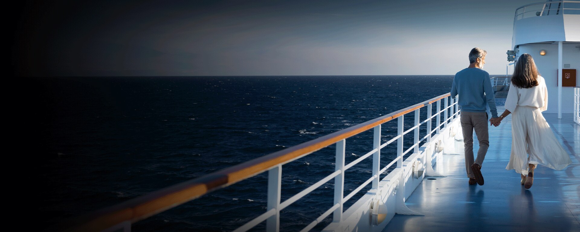 Couple holding hands while walking on a luxury Regent cruise ship