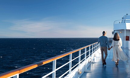 Couple holding hands while walking on a luxury Regent cruise ship