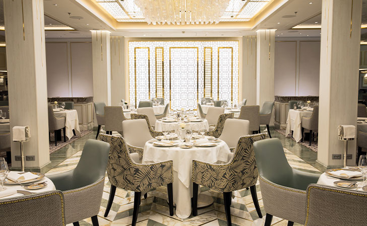 the main dining area in compass rose with a large decorating chandelier with many crystals and chevron tiled floors